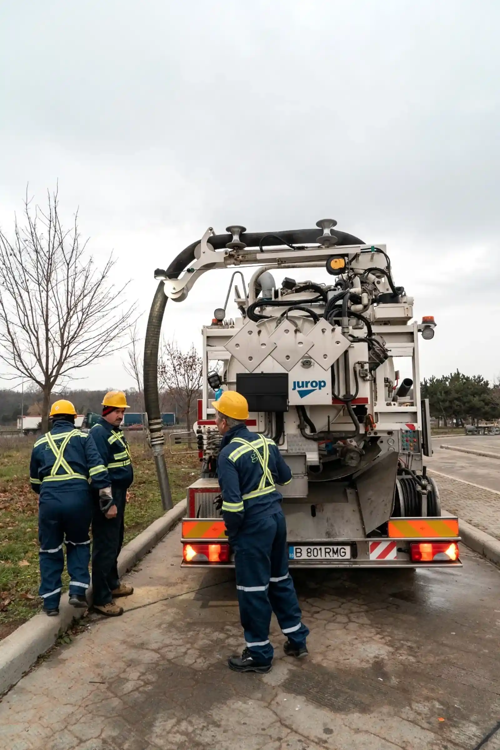 Three operators at the rear of the JUROP unit, preparing the suction hoses