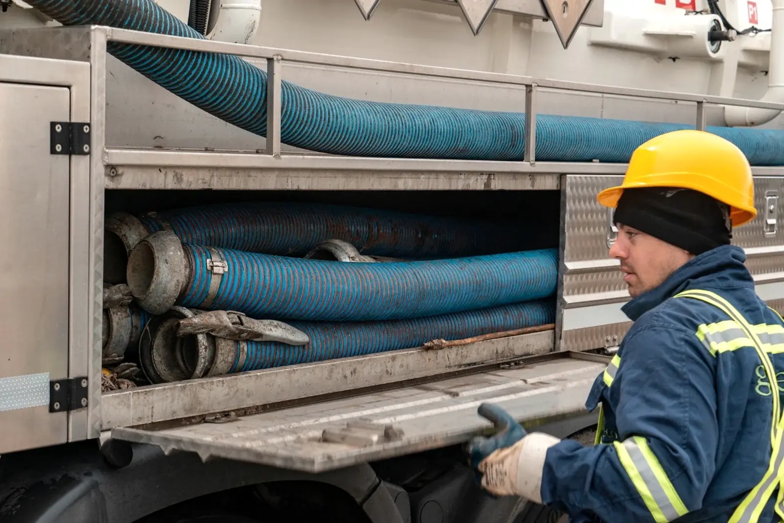 Close-up of an operator handling the suction hoses of a vacuum truck